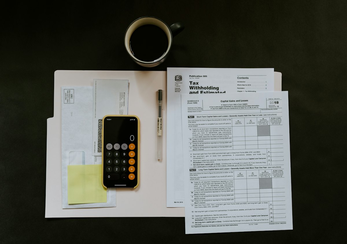 Printed forms, a calculator and a phone on a dark desk