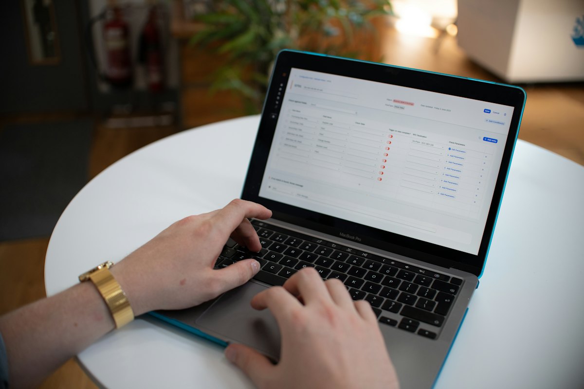 A person typing on a laptop at a white table