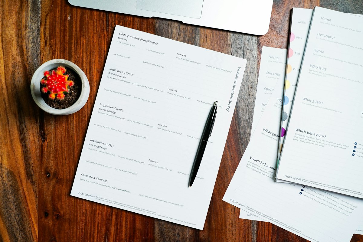 Papers spread across a wooden table with a pen