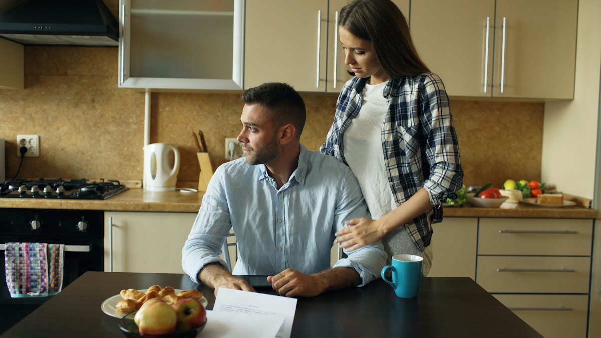 A man and a woman going through papers together at a kitchen counter