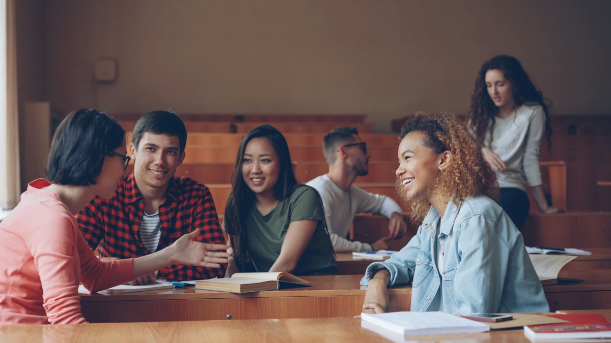 Students gathered around a laptop in a lecture hall